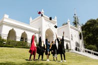 Group of graduates celebrate by tossing caps outside a historic building